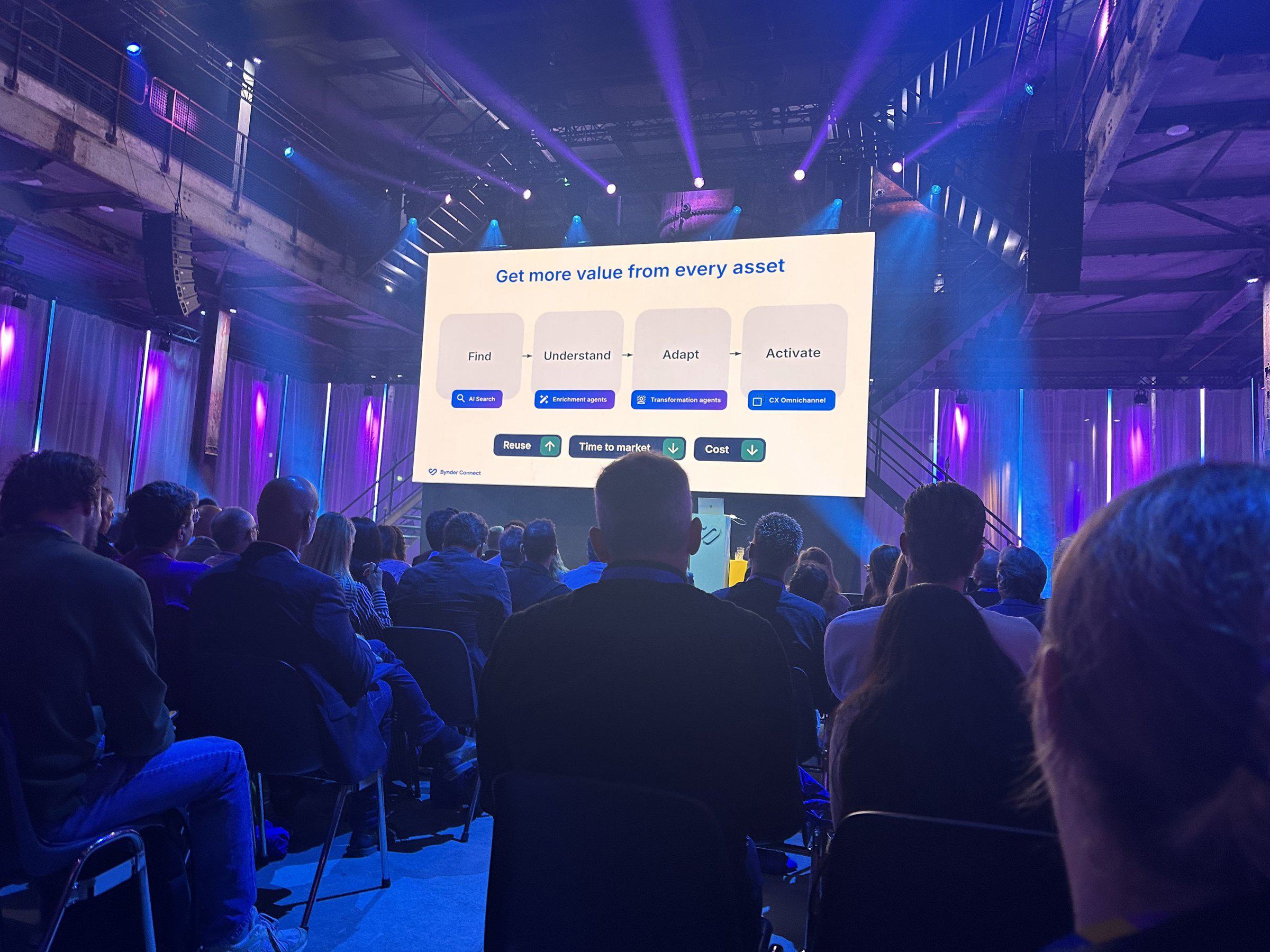 Attendees fill the SugarFactory hall in Amsterdam as a Bynder Connect 2026 slide shows four steps: Find, Understand, Adapt, and Activate.